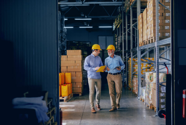 Due persone passeggiano per l’azienda parlando di raccolta dati della produzione aziendale